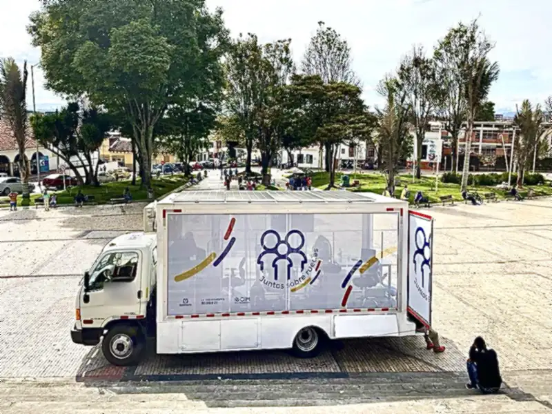 Vehículo oficina con paneles solares en el techo, estacionado en una plaza pública
